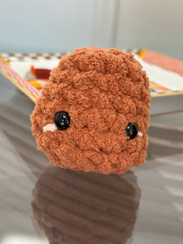 Crochet chicken nugget plush toy in golden brown with textured breading detail and safety eyes